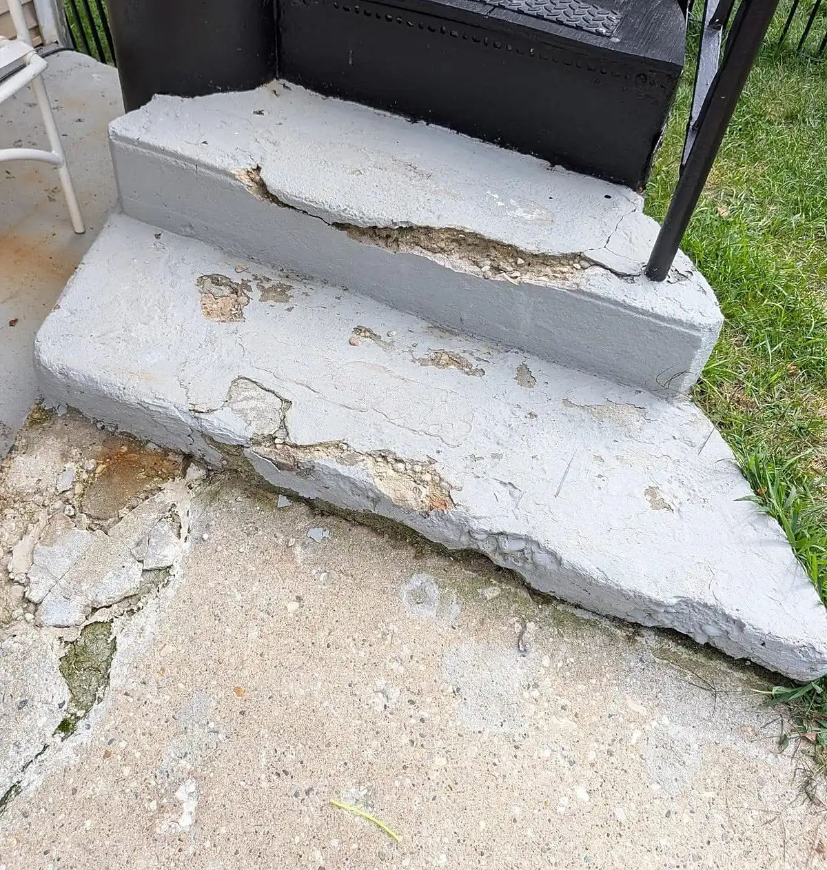 Painted concrete steps with the surface spalling away in sheets, exposing the aggregate underneath.