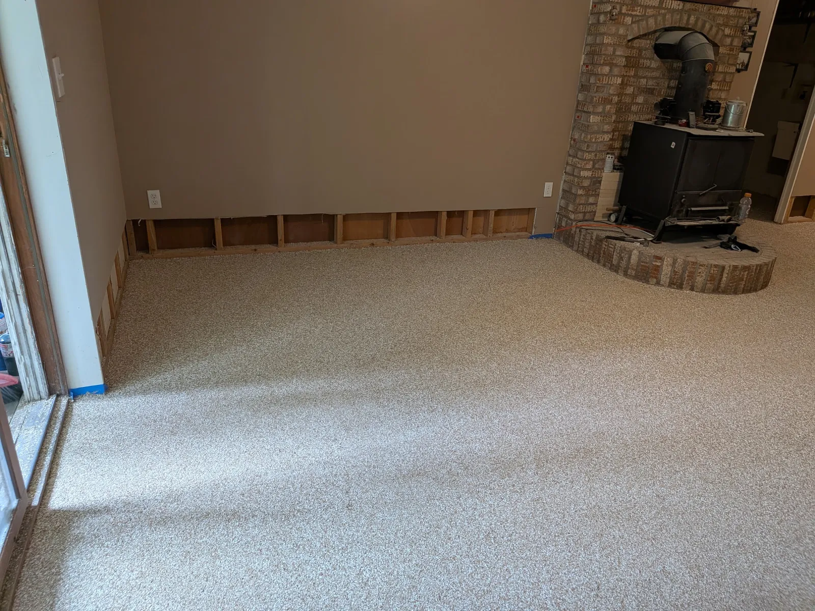 Flake epoxy floor finished tight against the brick hearth of a wood stove, baseboard trim off the walls.