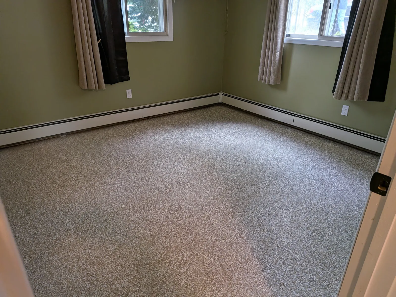 Second bedroom with two curtained windows and a continuous beige flake epoxy floor.