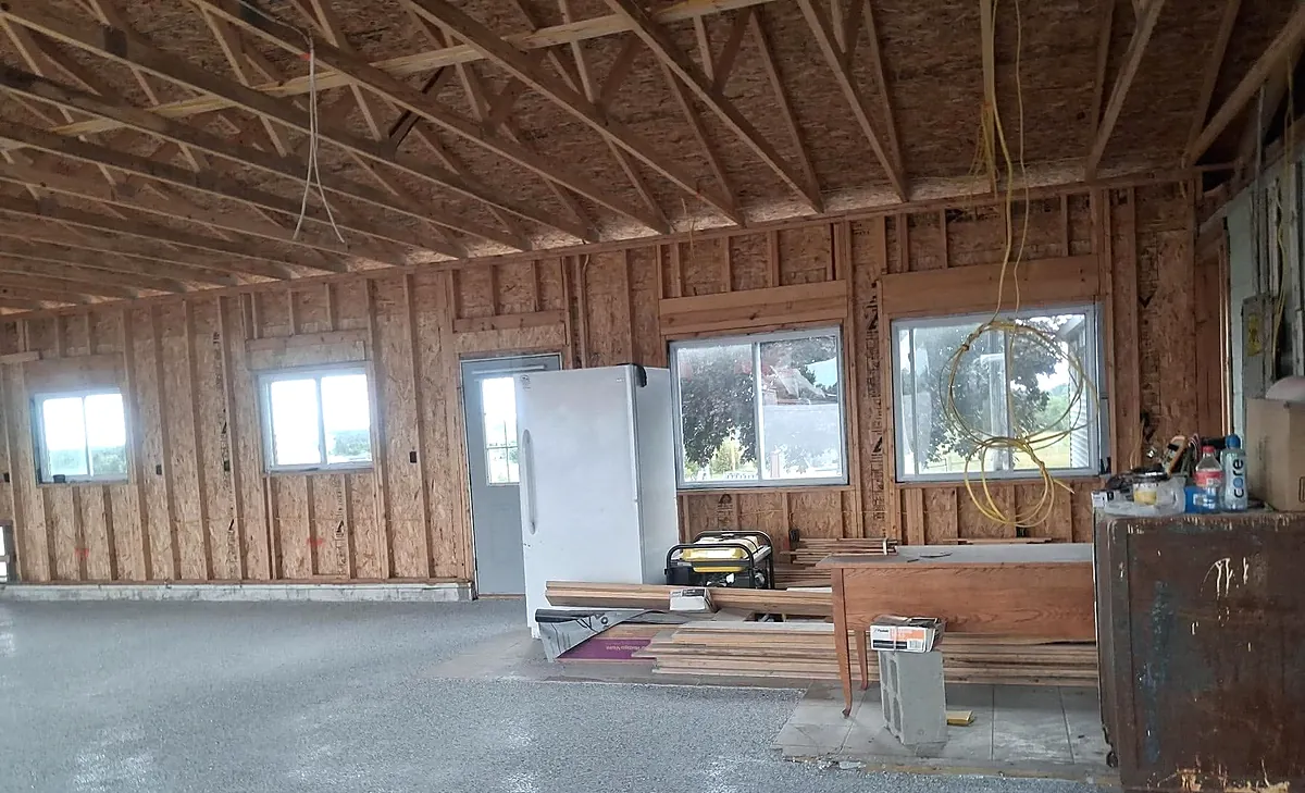 Finished grey flake epoxy floor seen at an angle across a framed pole barn, with daylight reflecting off the coated surface.